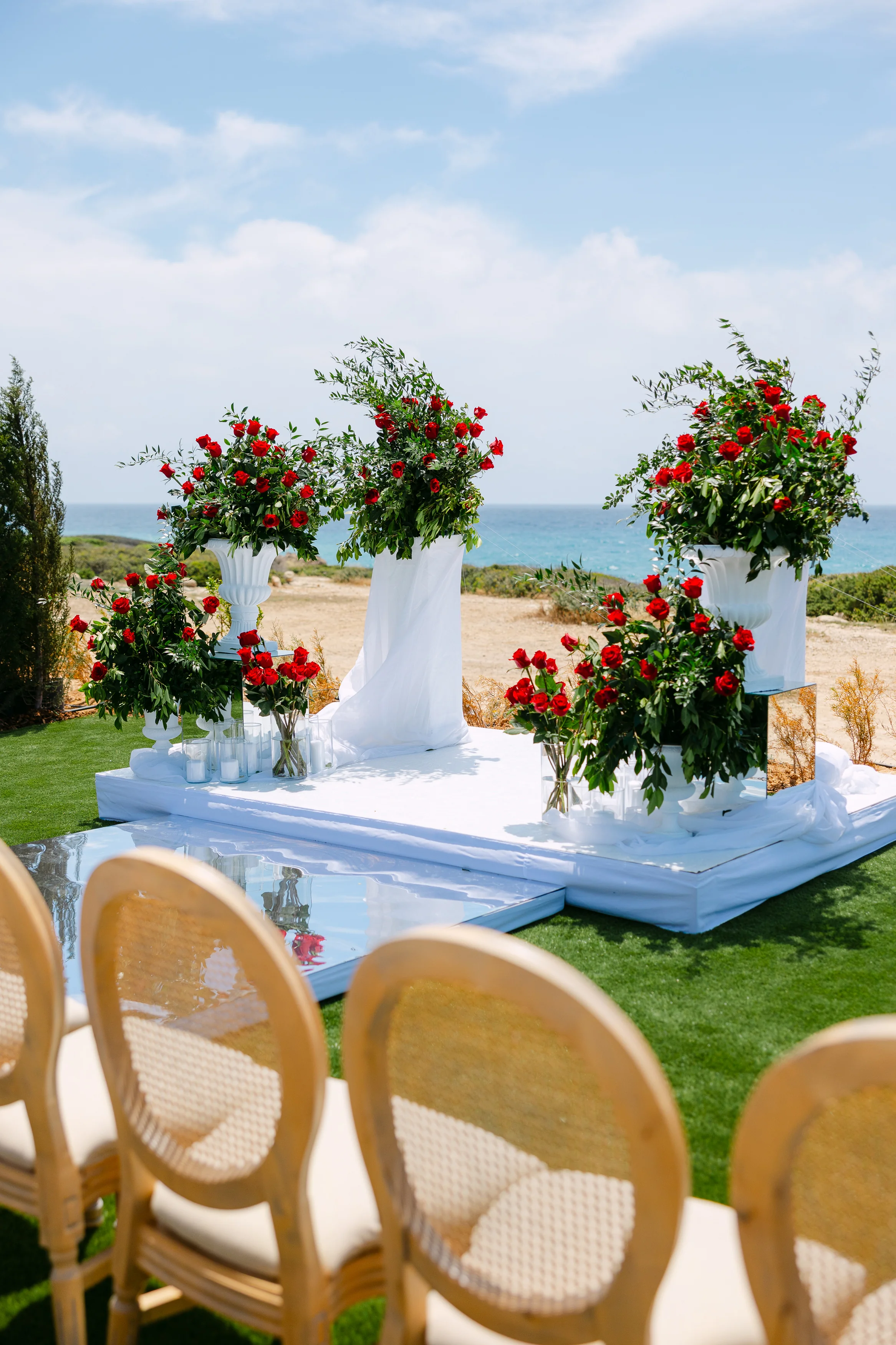 Close view of the floral altar pedestals at Ozea with red roses and white plinths.