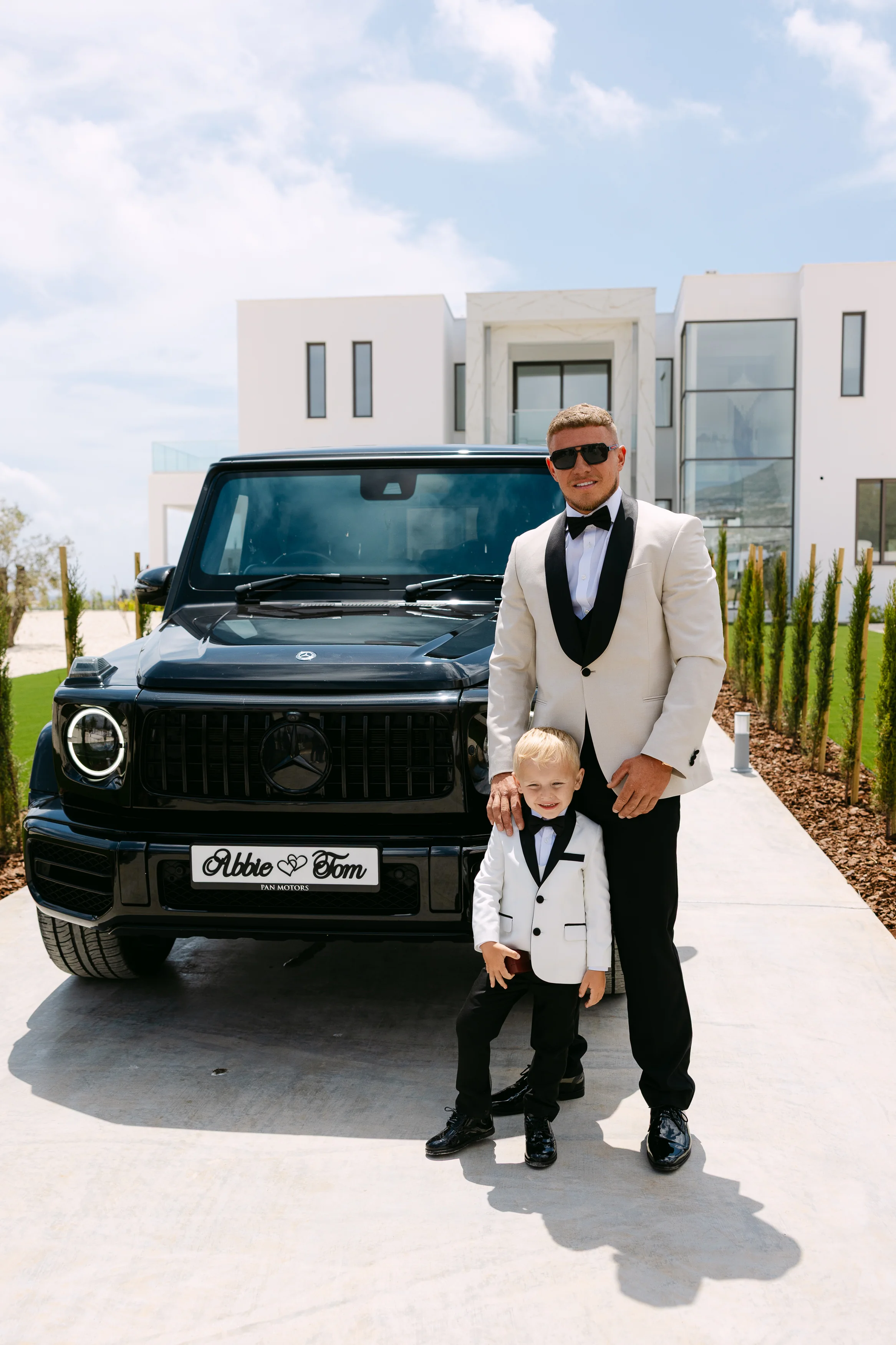 Groom standing with his young son beside a personalised Mercedes G-Wagon at OZEA.