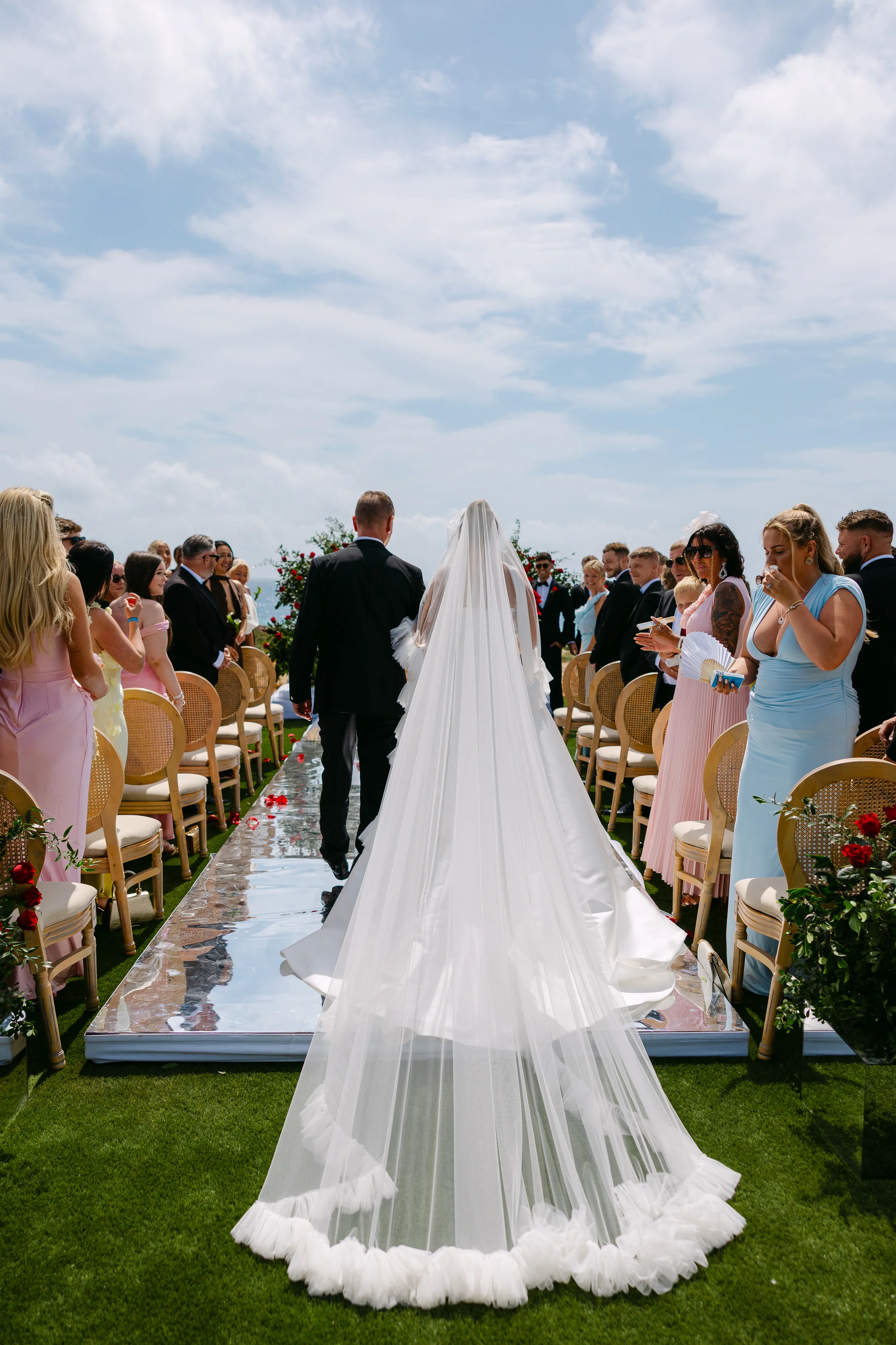 Bride walking down the mirrored aisle with her father at Ozea, full veil trailing behind.