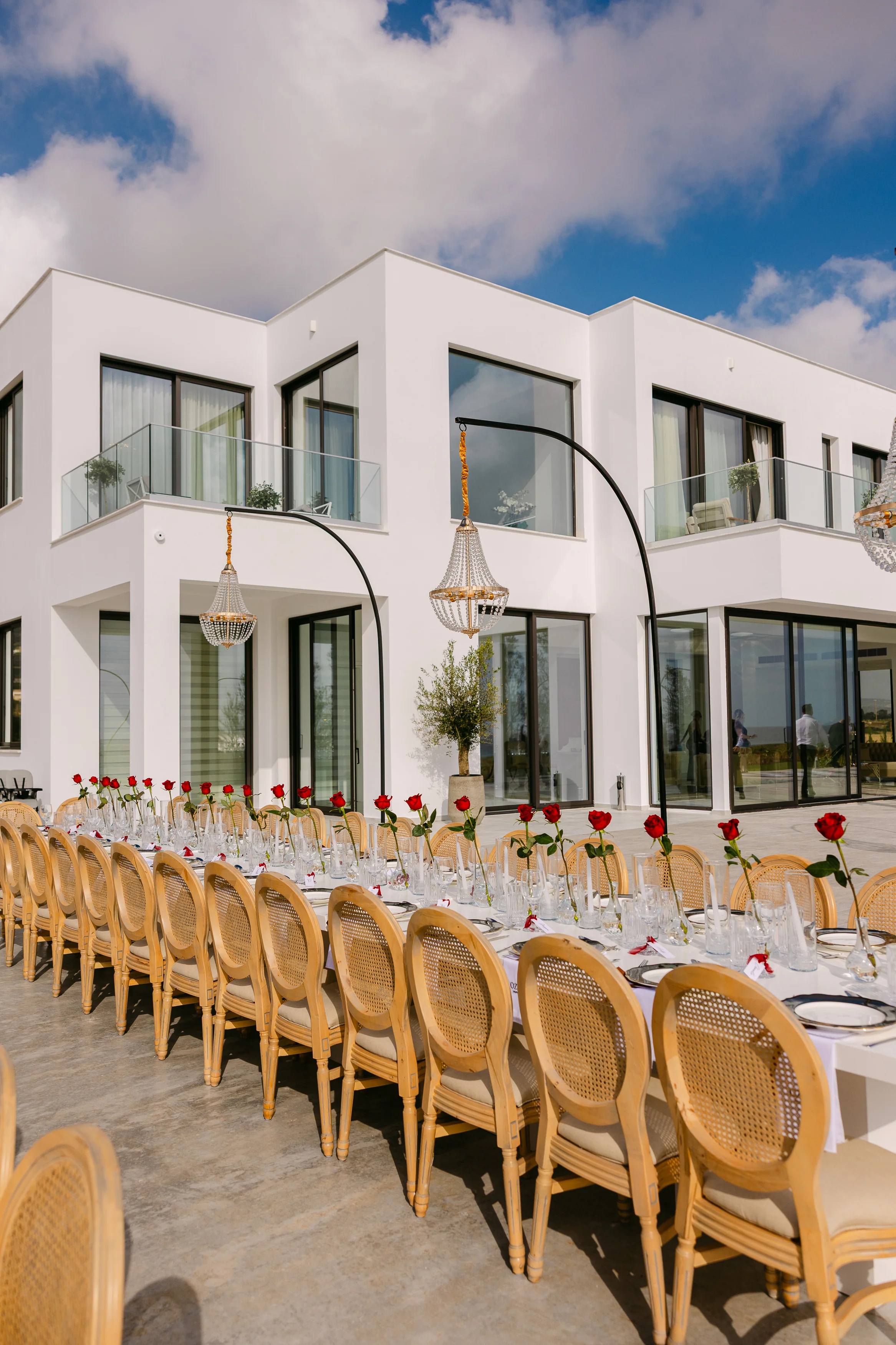 Exterior of the villa at OZEA with a long banquet table styled along the terrace and red roses at every setting.