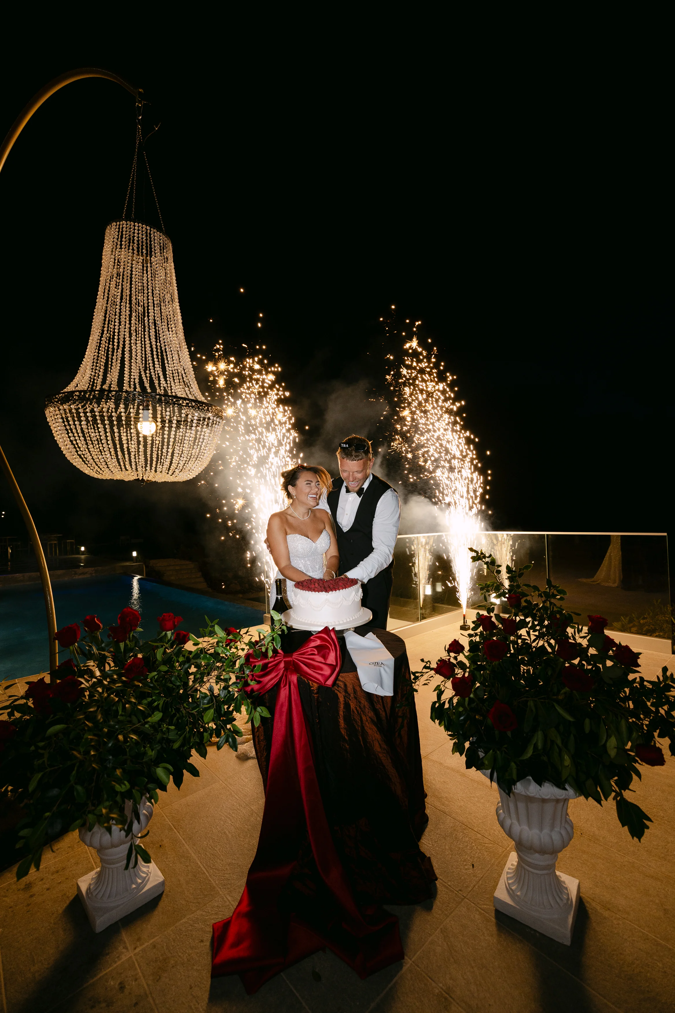 Bride and groom cutting the cake at night at Ozea with sparkler fountains behind.